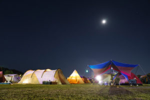夜のキャンプ場にトンネル型テントが設置されているイメージ